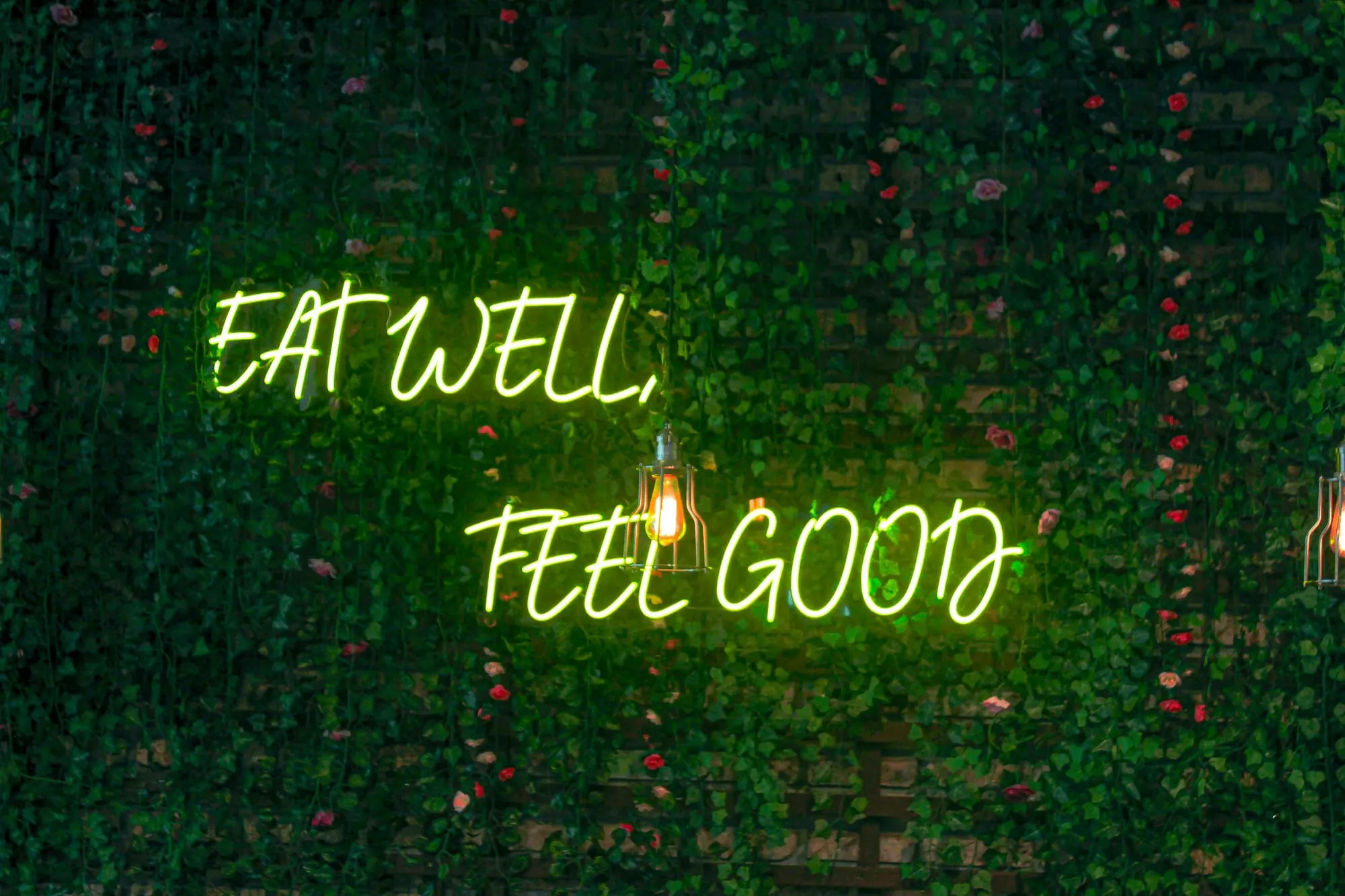 A neon sign mounted on a green plant wall — a storefront at street level